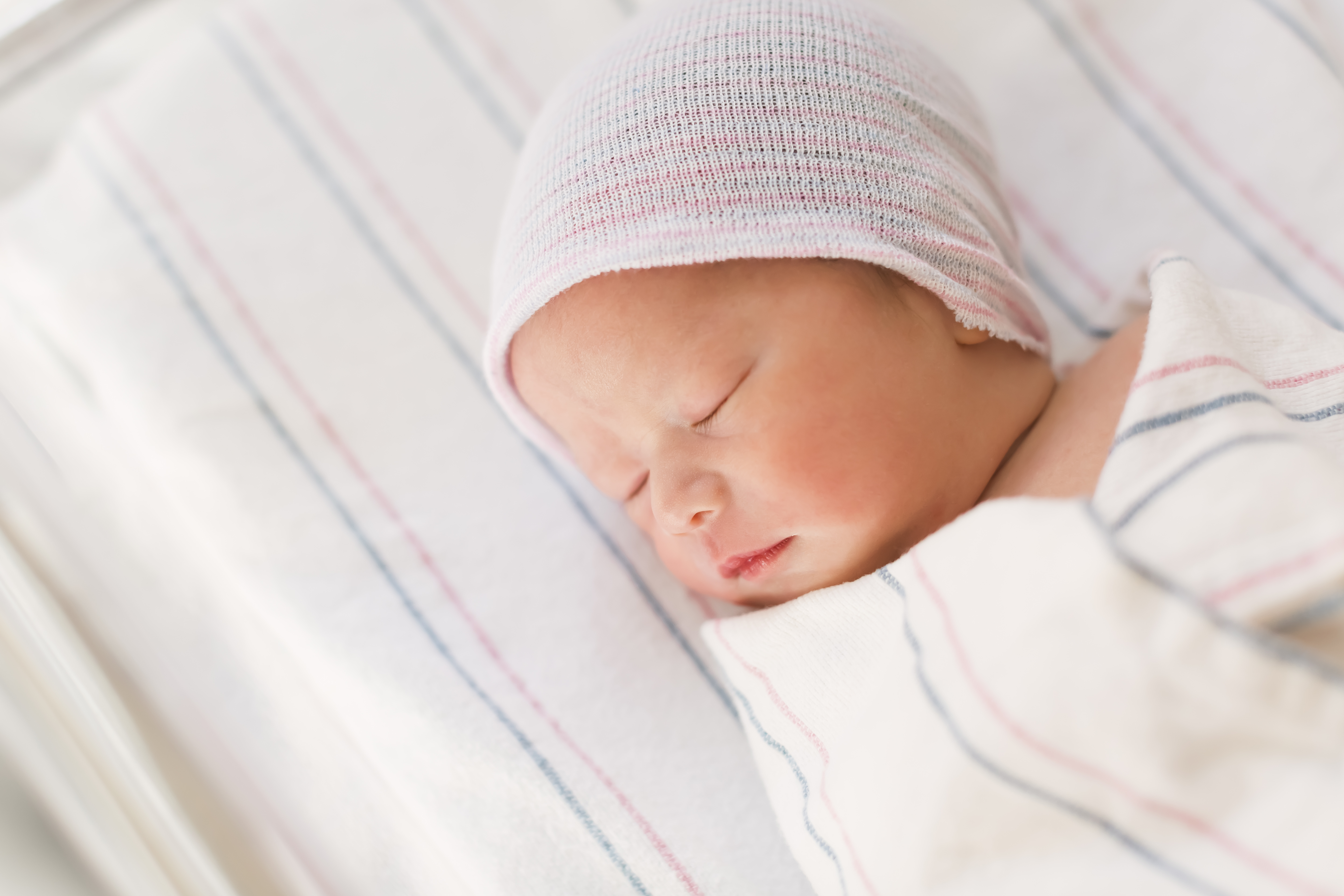 Newborn infant baby boy swaddled after birth lying in his hospital bed